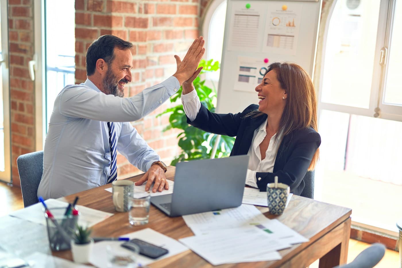 Two colleagues high-fiving at their desk