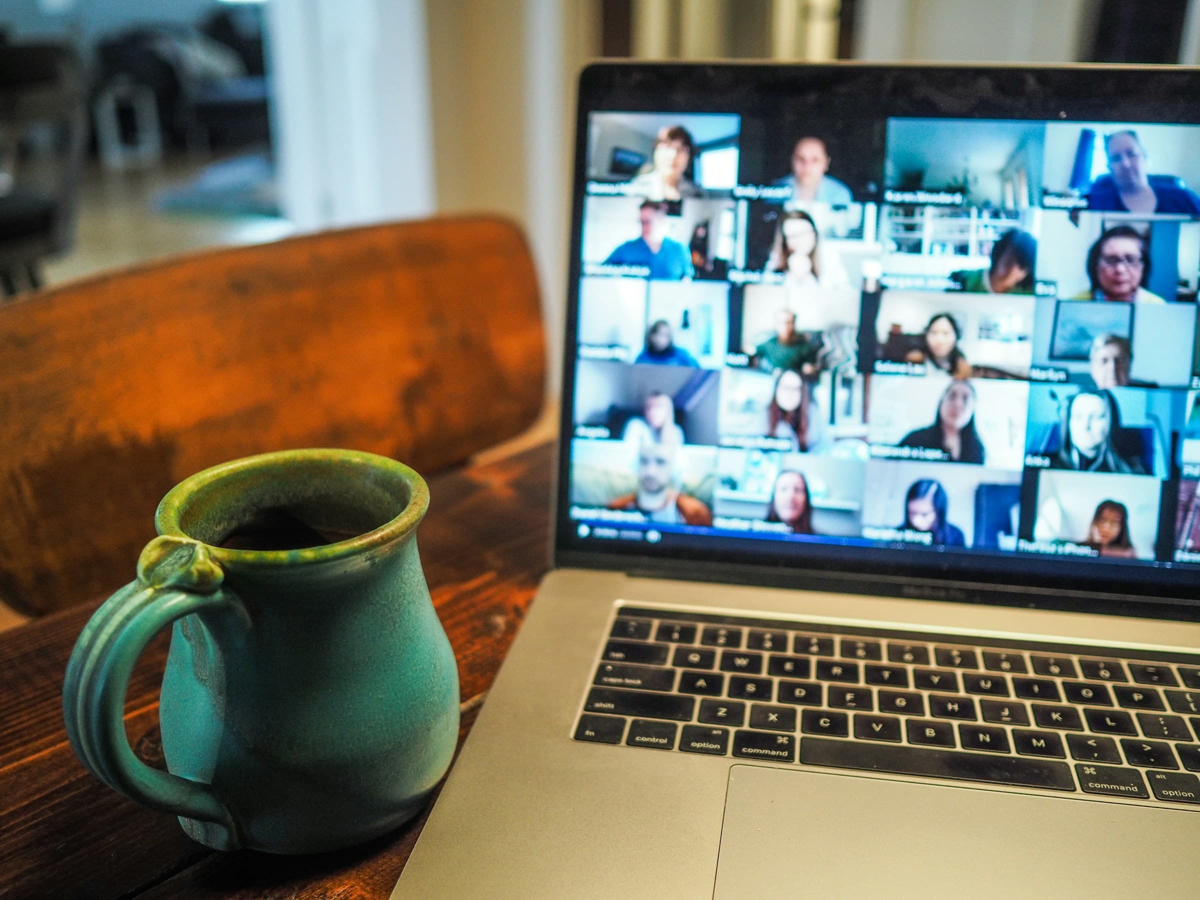 A laptop on a desk showing a video call with many participants