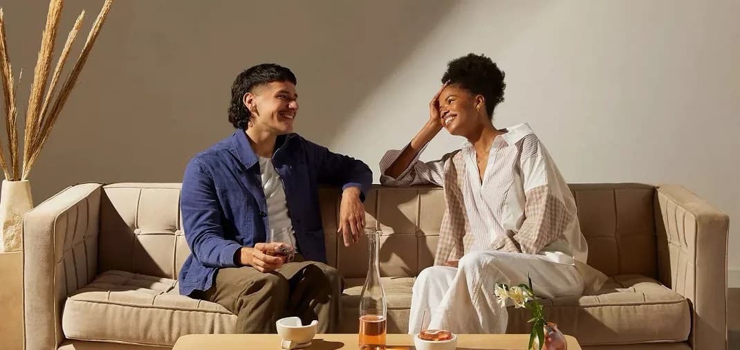 Two people talking and laughing together on a sofa